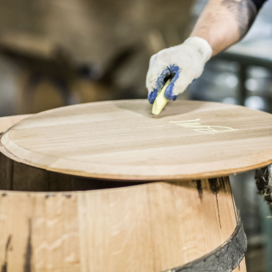 Master cooper writing in chalk on a barrel head